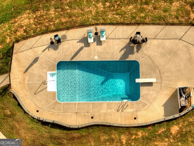 view of pool with a diving board and a patio