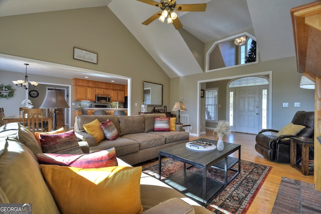 living room with high vaulted ceiling, light wood-type flooring, and ceiling fan with notable chandelier