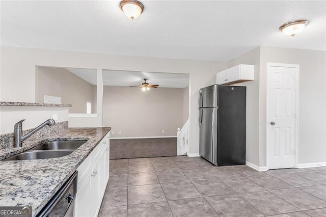 kitchen with stainless steel appliances, white cabinetry, sink, light stone counters, and ceiling fan