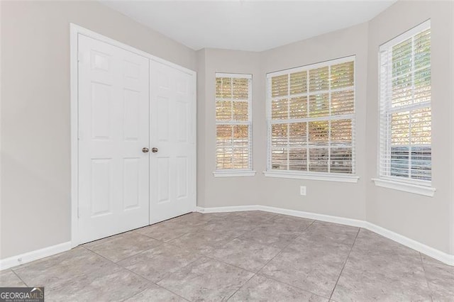 unfurnished bedroom featuring light tile patterned floors, multiple windows, and a closet