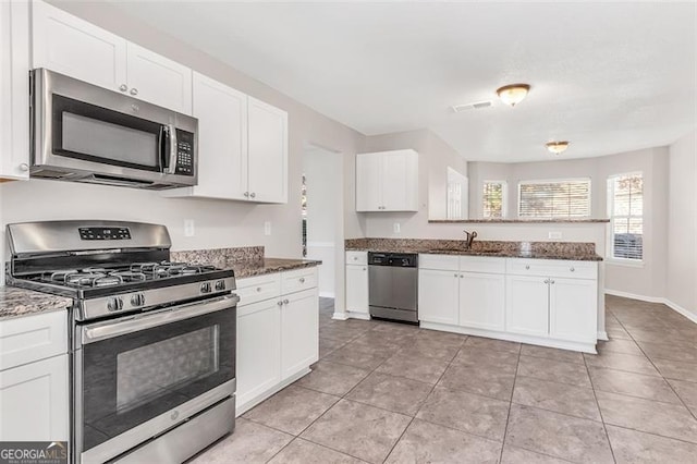 kitchen featuring stainless steel appliances, white cabinetry, sink, dark stone countertops, and light tile patterned floors