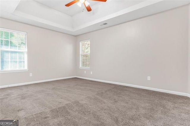 unfurnished room featuring carpet flooring, ceiling fan, and a raised ceiling