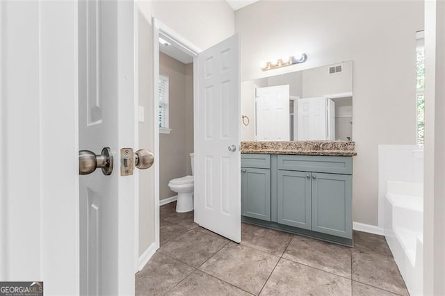 bathroom featuring toilet, vanity, a tub, and tile patterned flooring