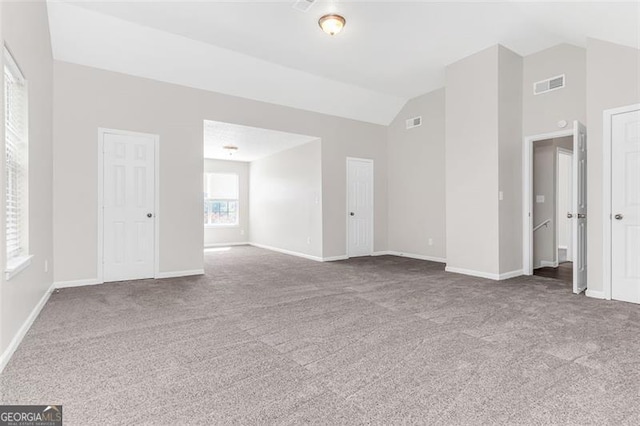 carpeted spare room featuring high vaulted ceiling