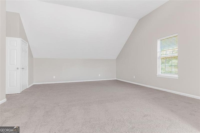 additional living space featuring light carpet and vaulted ceiling