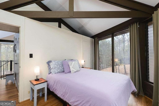 bedroom featuring hardwood / wood-style flooring, lofted ceiling with beams, and multiple windows