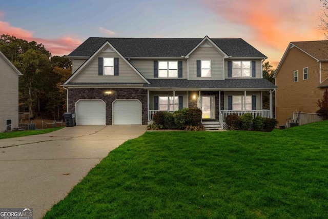 view of front of property with a garage, a lawn, and a porch