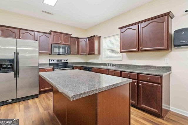 kitchen featuring a kitchen island, appliances with stainless steel finishes, sink, and light hardwood / wood-style floors