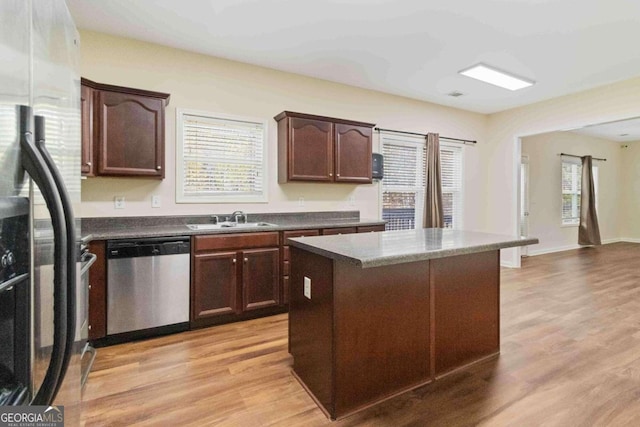 kitchen featuring stainless steel appliances, a kitchen island, dark brown cabinetry, sink, and light hardwood / wood-style floors