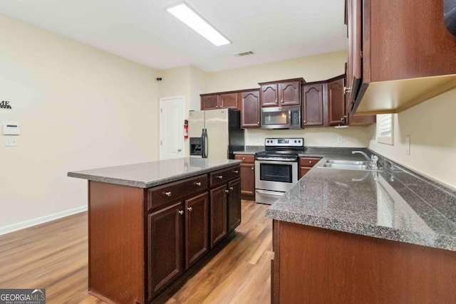 kitchen featuring a kitchen island, sink, light wood-type flooring, and appliances with stainless steel finishes