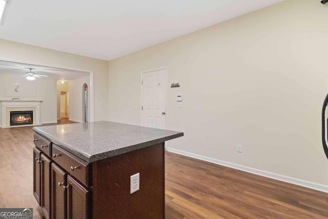 kitchen with a kitchen island, wood-type flooring, dark brown cabinets, and ceiling fan