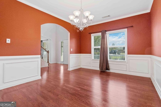 unfurnished room with wood-type flooring, crown molding, and an inviting chandelier