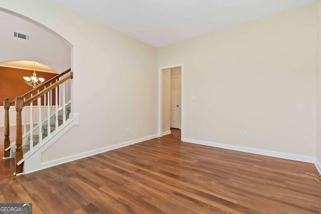 unfurnished room with wood-type flooring and an inviting chandelier