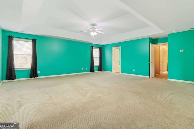 unfurnished bedroom featuring light colored carpet, ceiling fan, and a raised ceiling