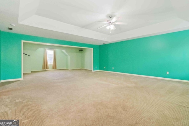 empty room featuring ceiling fan, carpet floors, and a tray ceiling