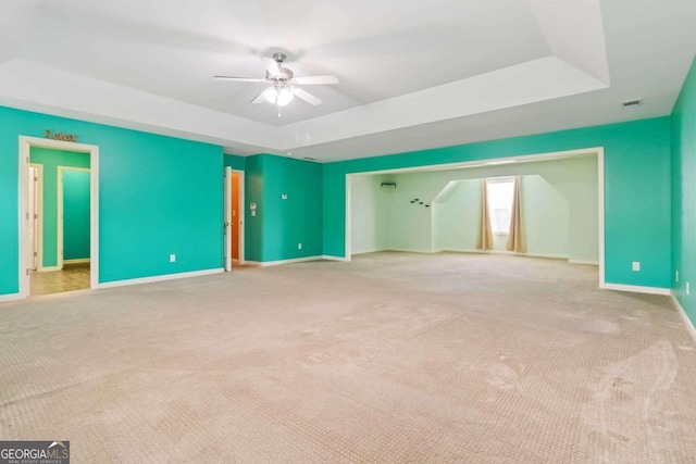 interior space featuring light colored carpet, ceiling fan, and a tray ceiling