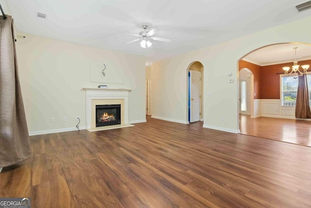 unfurnished living room featuring dark wood-type flooring, ceiling fan with notable chandelier, and crown molding