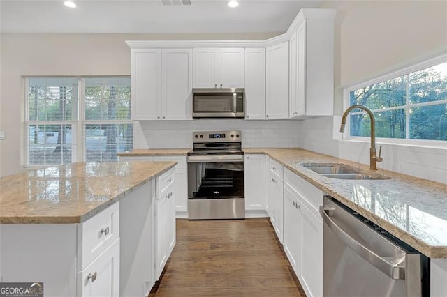 kitchen featuring sink, light stone counters, dark hardwood / wood-style floors, white cabinets, and appliances with stainless steel finishes