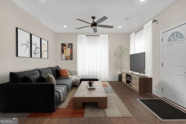 living room featuring ceiling fan and dark wood-type flooring