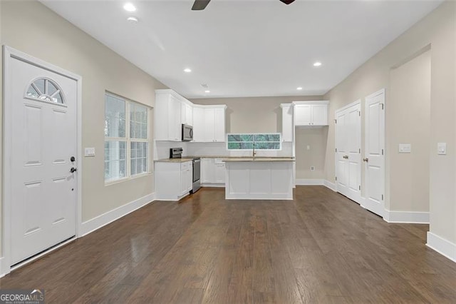 kitchen with a healthy amount of sunlight, white cabinetry, stainless steel appliances, and dark wood-type flooring