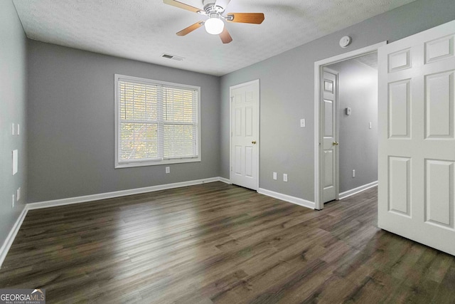 unfurnished bedroom featuring ceiling fan, a textured ceiling, and dark hardwood / wood-style flooring