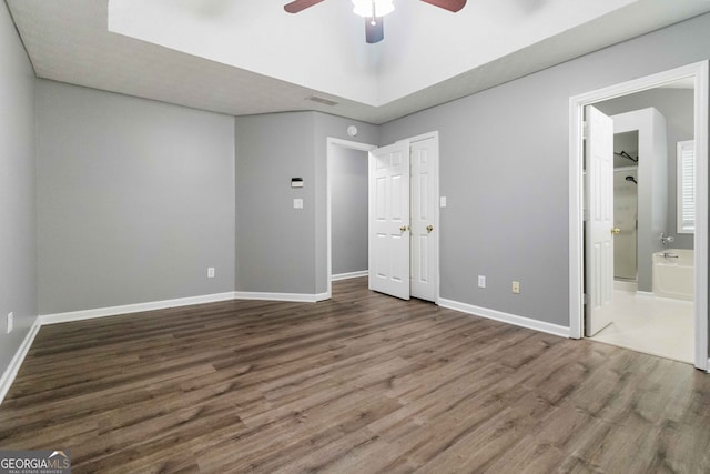 unfurnished bedroom with connected bathroom, hardwood / wood-style floors, and ceiling fan