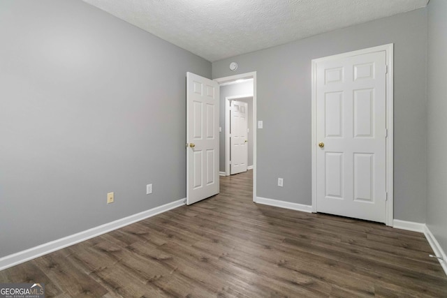 unfurnished bedroom with dark hardwood / wood-style floors and a textured ceiling