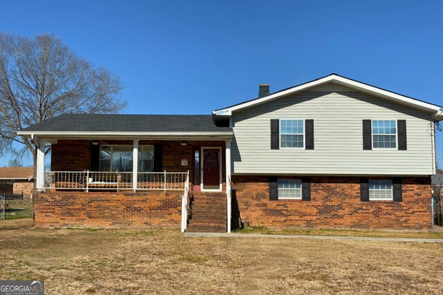 split level home featuring covered porch and a front yard