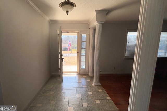 entrance foyer with baseboards, ornamental molding, stone finish floor, and ornate columns