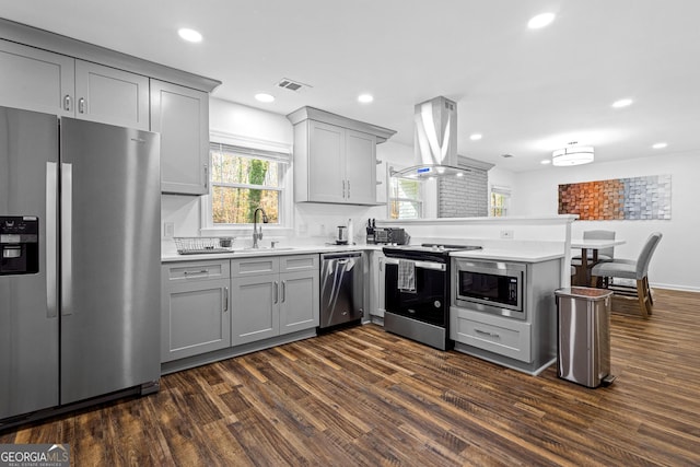 kitchen featuring kitchen peninsula, stainless steel appliances, dark wood-type flooring, and island range hood