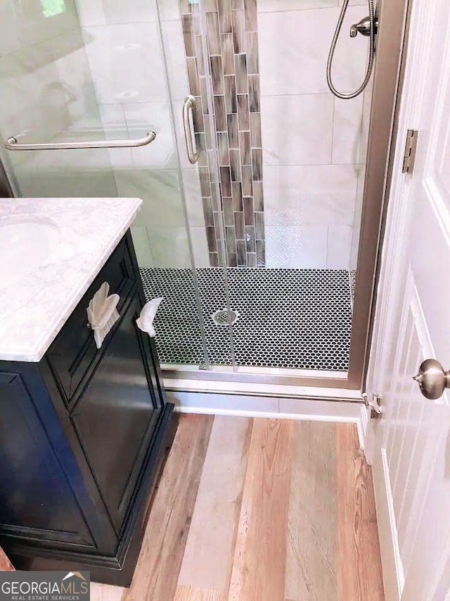 bathroom featuring vanity, wood-type flooring, and a shower with door