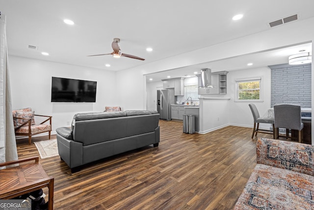 living room with dark hardwood / wood-style flooring, ceiling fan, and sink