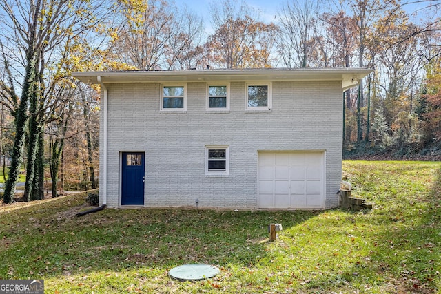 back of house featuring a garage and a yard