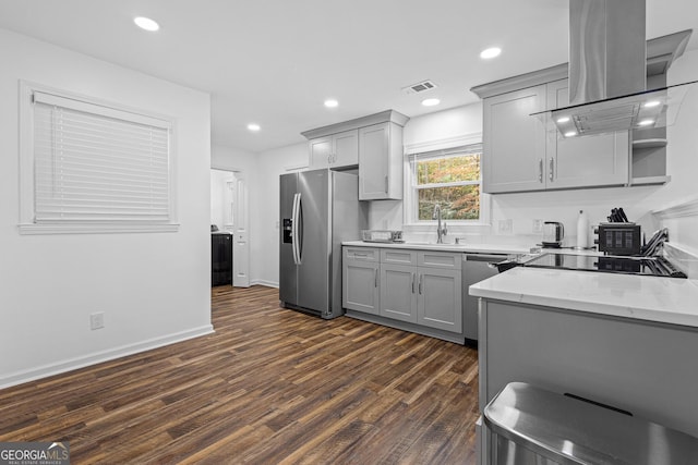 kitchen featuring gray cabinetry, light stone countertops, island exhaust hood, and appliances with stainless steel finishes