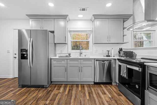 kitchen featuring island exhaust hood, appliances with stainless steel finishes, sink, and gray cabinetry