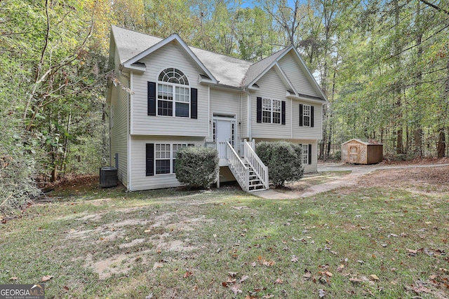 bi-level home featuring a front yard, central AC unit, and a storage shed