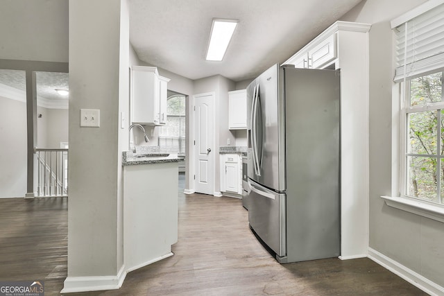 kitchen with white cabinets, stainless steel refrigerator with ice dispenser, wood-type flooring, and light stone counters