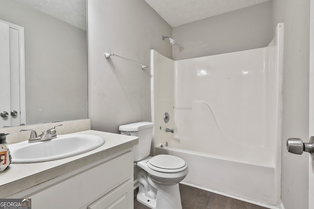 full bathroom featuring vanity, a textured ceiling,  shower combination, hardwood / wood-style flooring, and toilet