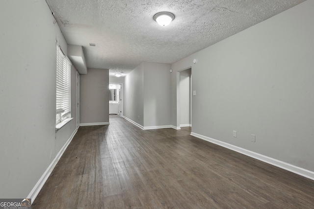 spare room featuring dark wood-type flooring and a textured ceiling