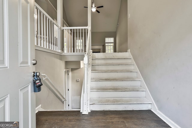 stairs with ceiling fan, wood-type flooring, and high vaulted ceiling