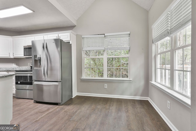 kitchen with white cabinets, stainless steel appliances, lofted ceiling, and light hardwood / wood-style floors