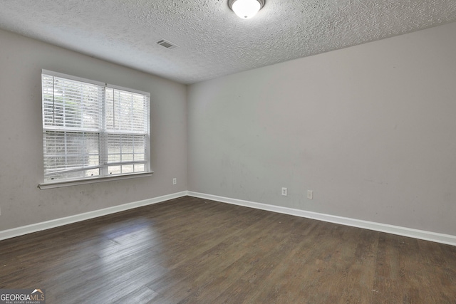 empty room with dark hardwood / wood-style flooring and a textured ceiling