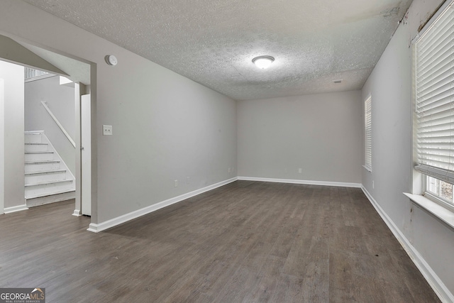 spare room featuring dark hardwood / wood-style flooring and a textured ceiling