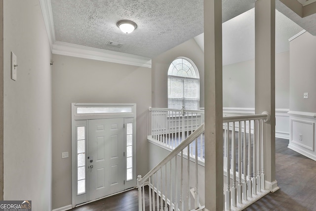 entryway with dark hardwood / wood-style flooring, a textured ceiling, vaulted ceiling, and ornamental molding