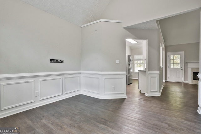 spare room with lofted ceiling, a textured ceiling, and dark hardwood / wood-style floors