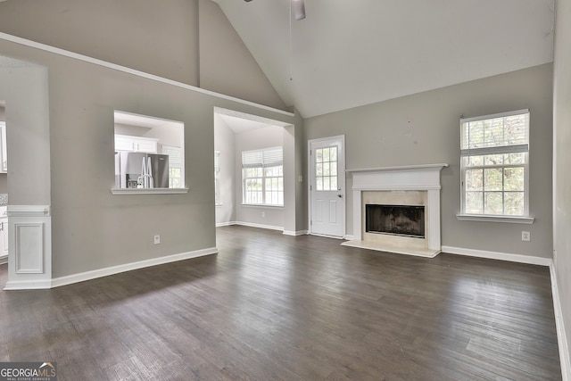 unfurnished living room featuring high vaulted ceiling, dark hardwood / wood-style flooring, and a wealth of natural light