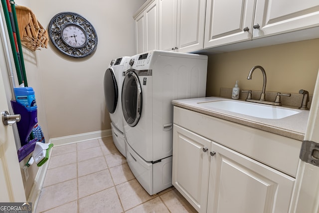 laundry area featuring washing machine and dryer, cabinets, sink, and light tile patterned floors