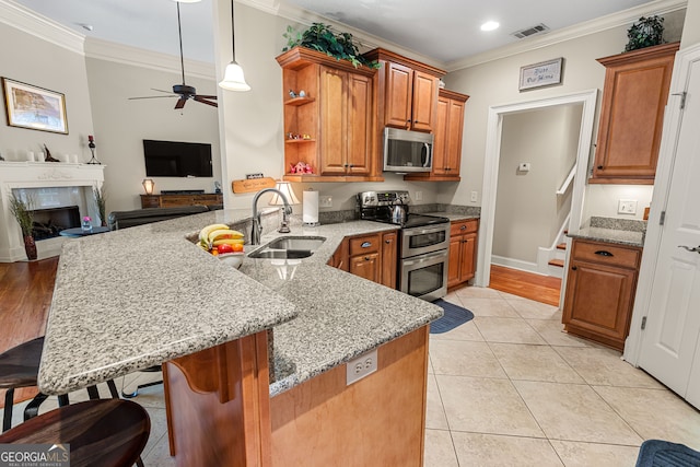 kitchen featuring kitchen peninsula, sink, a kitchen breakfast bar, ceiling fan, and appliances with stainless steel finishes