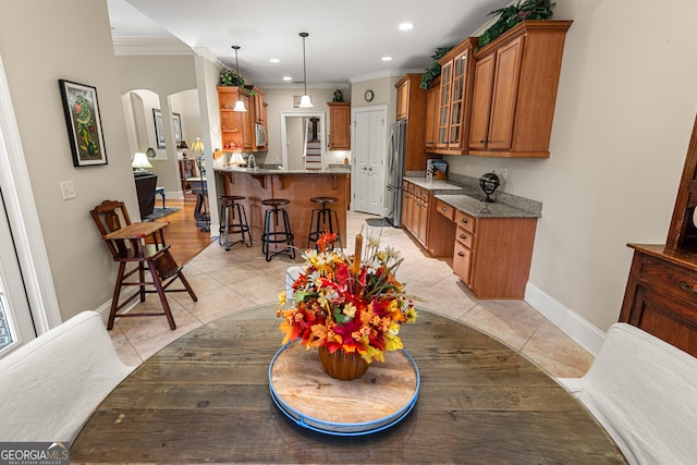 kitchen with stainless steel fridge, crown molding, hanging light fixtures, a breakfast bar, and kitchen peninsula