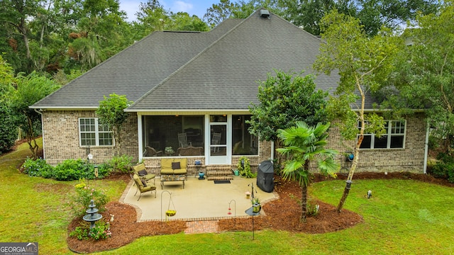 rear view of house with a patio area, a sunroom, and a lawn